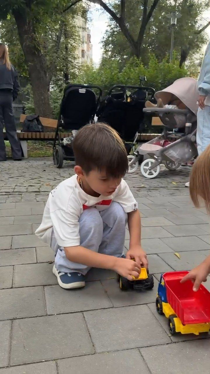 Мальчик играет с игрушечным грузовиком на плитке